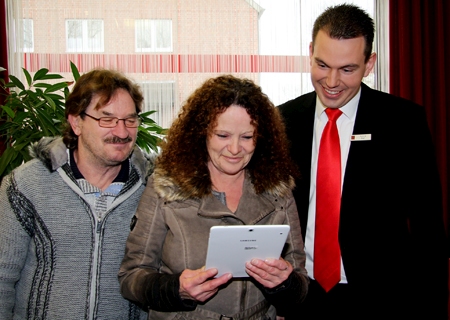 Ramona Vonderlind hält ihr neues Tablet in Händen. Ehemann Achim (l.) und Patrick Beyl (r.) freuen sich mit der glücklichen Gewinnerin.