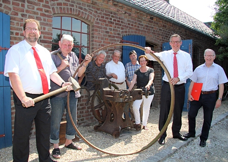 An der alten Stauchmaschine der Dorfschmiede, mit der Eisenringe für Wagenräder wieder passend gemacht wurden (v.l.n.r.): Volker Oppers, Johannes Peters, Klaus Karmann, Fritz Nühlen, Dr. Robert Moog und Irmgard Graeven (alle Geschichtsverein) sowie Bernd Zibell und Wilhelm van gen Hassend von der Kulturstiftung Sparkasse am Niederrhein.