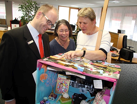 Marianne Hilke und Petra Kunst (von rechts) vom Römermuseum schauen zusammen mit Gerd Heursen, dem stellvertretenden Leiter der Sparkasse am Europaplatz, in Rebeccas Museumsbox. 