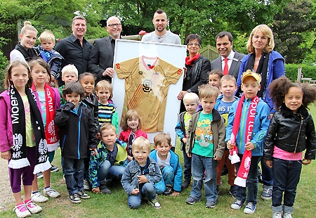 1000 Euro brachten Georg Grozer (Mitte) und Ralf Dommasch (links daneben) mit zur Trikotübergabe im evangelischen Kindergarten in Eick. Zusammen mit seiner Sparkassenberaterin Petra Nowack (rechts daneben) hatte Georg Grozer die Idee, das Trikot zugunsten von Kindern zu versteigern. Kindergartenleiterin Dagmar Bary (ganz rechts) und Giovanni Malaponti (links daneben), Vorstandsvorsitzender der Sparkasse, bedankten sich für die schöne Idee.