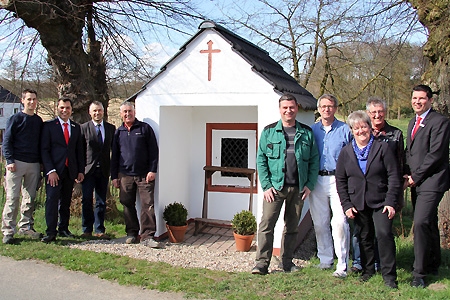 Christian Paßens (v.l.n.r.), Sparkassenchef Giovanni Malaponti, Bürgermeister Heiko Schmidt, Theo Theissen, Brudermeister Gerd Geuyen, Michael Bongarts, Ortsvorsteherin Hildegard Pieper, Hans-Josef Nobis und Geschäftsstellenleiter Oliver Heger am kernsanierten Heiligenhäuschen in Labbeck.