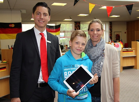 Jannis Broß (Mitte) hat beim Gewinnspiel der Sparkasse am Niederrhein ein Tablet gewonnen. Azubi Justin Schnabl gratuliert herzlich. Mutter Daniela Broß freut sich mit ihrem zehnjährigen Sohn.