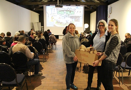 Diakonie-Flüchtlingsberaterin Heike Pullich-Stöffken (v.l.n.r.) und die Sparkassenmitarbeiterinnen Monika Pogacic und Annika Schmitz zeigen die Knabbertüten, die den Gästen die Kino-Vorstellung im Siegfriedmuseum versüßten.