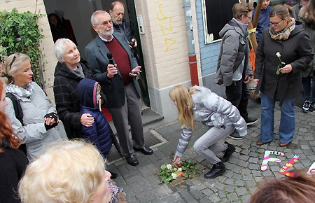 Eine Schülerin der Justus-von-Liebig-Hauptschule legt Blumen am Stolperstein für Wilhelm Flecken nieder. Dessen Tochter Wilma Müller (2. v.l.) und ihr Enkel Jonas waren zur feierlichen Steinverlegung vor dem Haus an der Pfefferstraße 6 gekommen. Dr. Bernhard Schmidt (rechts daneben) erinnerte an den 1942 ermordeten NS-Widerstandskämpfer aus Moers.