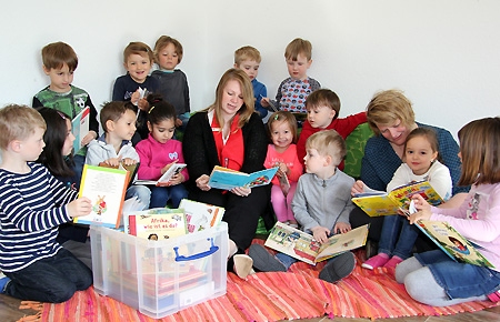 Geschäftsstellenleitern Sara Deckers (Mitte) liest in der AWO-Kita die Geschichte vom bunten Elefanten Elmar vor. Das Buch ist eines von vielen aus der neuen Bücherkiste der Stiftung Lesen, die Sara Deckers jetzt der Leiterin Michaela Winnekens (r.) überreichte.