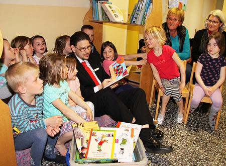 Geschäftsstellenleiter Julian de Vries liest im St.-Theresia-Kindergarten die Geschichte vom bunten Elefanten Elmar vor. Das Buch ist eines von vielen aus der neuen Bücherkiste der Stiftung Lesen, die Julian de Vries und Monika Pogacic (r.) jetzt der Leiterin Ulrike Schiffer (daneben) überreichten.