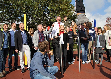 Mit einem Handstand und vielen anderen Übungen zeigte Dario Bones, was alles am neuen Calisthenics-Sportgerät am JSG möglich ist. Nach links: Dr. Susanne Marten-Cleef sowie Katrin Steffans und Bernd Zibell von der Sparkasse trainierten unter der Aufsicht von Franz Frings (5.v.l.) ein wenig mit. 