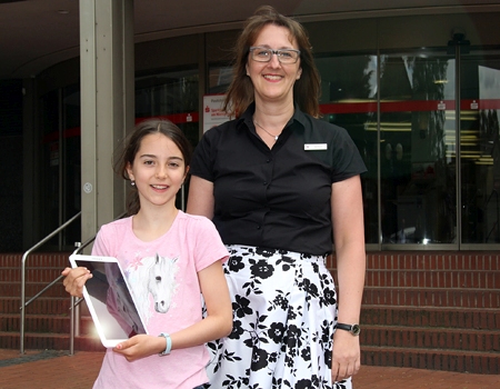 Die zehnjährige Leni Wohlgemuth zeigt ihr neues Tablet. Das hat sie bei einem Gewinnspiel der Sparkasse am Niederrhein gewonnen. Kundenberaterin Susanne Hempen gratuliert herzlich.