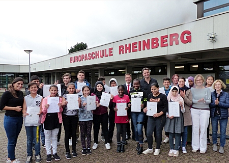 Strahlende Gesichter an der Europaschule: 21 Flüchtlingskinder bestanden die Sprachprüfung der VHS. Ganz links: Hülya Atasoyi, ganz rechts: Elisabeth Keggenhoff und (3.v.r.) Elke Vasel. Martin Reichert (10.v.r.) und Tim Rütters (links daneben) hatten zuvor die Zertifikate überreicht.  