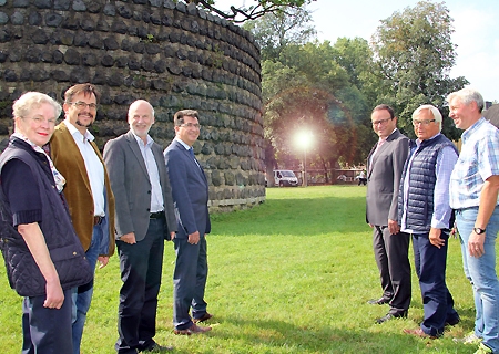 Bettina Raendchen und Ralf Winstroth von der Bürgerinitiative, Baudezernent Dieter Paus, Bürgermeister Frank Tatzel, Sparkassenvorstand Frank-Rainer Laake sowie Viktor Vervoort und Jupp Böckling stehen Spalier für die Laterne mit den zwei Strahlern, die den Platz am Pulverturm abends beleuchten.