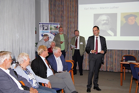 Dr. Christian Hecker (rechts) im Gespräch mit interessierten Zuhörern nach seinem Vortrag über Martin Luther als Finanzmarkt-Kritiker im Casino der Sparkasse am Ostring in Moers. Im Hintergrund links Dieter Zisenis vom Kirchlichen Dienst in der Arbeitswelt und Peter Mörbel von der Evangelischen Akademie im Rheinland (rechts).