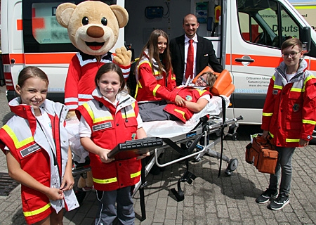 Zogen bei brüllender Hitze und mit Spaß ihre Einsatzjacken an (v.l.n.r.): Marlene, Bär Bruno, Aimee-Joana Jugendsprecherin Angelina Slavik, Darla (auf der Rettungsbahre), Jugendleiter Heiko Hennig und Vincent. 