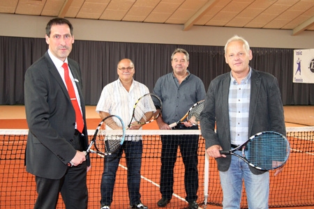 Norbert Kubik von der Sparkasse am Niederrhein, und der 1. Vorsitzende der Tennisabteilung Johannes Klöters stehen vor dem Netz, dahinter Beisitzer Joachim Stanitzek und der 2. Vorsitzende Andreas Wollmann. Im Hintergrund ist ein Teil der insgesamt 68 laufenden Meter der neuen Ballfang-Vorhänge zu sehen, deren Kauf die Sparkasse mit einer 2.000-Euro-Spende ermöglichte.