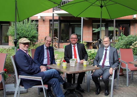 Genossen eine Tasse Kaffee unter dem neuen Sonnenschutz (v.l.n.r.): Andreas Riebe-Beier (Matthias-Jorissen-Haus), Mathias Türpitz (Erziehungsverein), Bernd Zibell (Sparkasse) und Hans-Wilhelm Fricke-Hein (Erziehungsverein). 