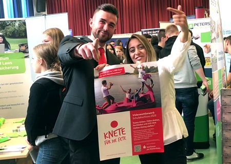 Die Azubis Leon Kandel und Ayse Degirmenci zeigen das Plakat zum Video-Wettbewerb „Knete für die Fete“. Bereits zum sechsten Mal lobt die Sparkasse am Niederrhein Party-Zuschüsse von 1.000, 750 und 500 Euro für die Abschlussjahrgänge von weiterführenden Schulen aus. Alle Informationen auf der Homepage der Sparkasse, einfach Knete ins Suchfeld tippen.