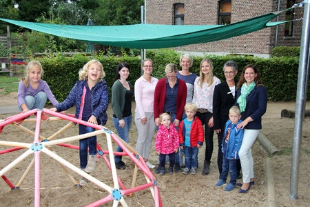 Kinder, Erzieherinnen und Eltern freuen sich über das neue, rund sechs mal vier Meter große Sonnensegel auf dem Außengelände des Kindergartens Sankt Pantaleon in Lüttingen. Vorne turnen Kiara und Hanna. Klara, Richard und Jan stehen lieber bei den Großen. V.l.n.r.: Kindergartenleiterin Kelly Krams, Annika Wenten, Meike Pulheim, Stephanie Overfeld, Stefanie Buchmann, Birte Frie von der Sparkasse und Marina Jakobs.