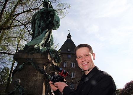 Auf Wunsch der Sparkasse am Niederrhein durchstreift Niederrhein-Dichter Christian Behrens mit Stift, Block und Kamera seit drei Wochen die Städte und Gemeinden im Geschäftsgebiet der Sparkasse. Hier ist er gerade am Denkmal der Henriette vor dem Moerser Schloss.