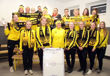 Die Damen-Fußballmannschaft des SV Borussia Veen empfängt Geschäftsstellenleiterin Kathrin Hüsch (hinten, Mitte) in der neuen Umkleide. Vereinsvorsitzender Heinz-Gerd Conrad und Projektleiter Dirk Hirschfeld (hinten, links) freuen sich über die 1.000-Euro-Spende von der Sparkasse am Niederrhein.