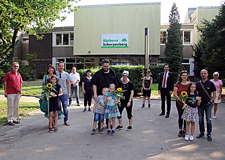 Preisverleihung beim Verein Bücherei Scherpenberg: Rosa (ganz links), Lea-Marie (Mitte) und Eda (ganz rechts) erhielten für ihre Geschichten je einen Gutschein und eine Sonnenblume. Mit dabei: ihre Eltern und Geschwister sowie die Ehrenamtlichen des Vereins um Daniela Brix (6.v.l.). Christian Faber (5.v.r.) überreichte die Preise.