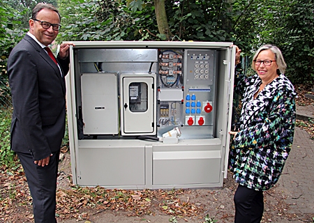 Ulrike Theußen, Geschäftsführerin des Vereins ‚Freilichtspiele Amphitheater Birten“, mit Sparkassenvorstand Frank-Rainer Laake am neu installierten Stromkasten.