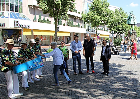 Überzeugten sich am Samstagvormittag selbst davon, wie gut die Künstler in der Innenstadt angenommen werden (v.r.n.l.): Giovanni Malaponti, Achim Reps, Michael Birr und Künstleragent Reinhard Nemitz, hier mit den Sunshine Coconuts und einer Passantin, die eine Münze in die Stahltrommel wirft.  