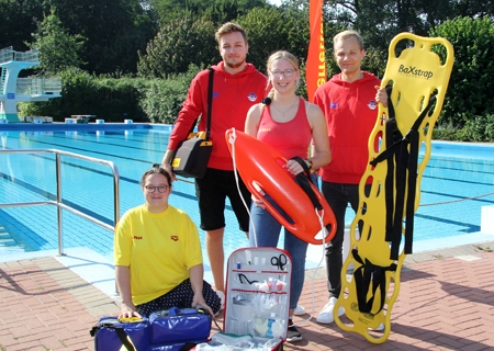 Ein Teil des DLRG-Teams mit einigen Rettungsutensilien, die in der Wachstation des Underberg-Freibads lagern. Die stellvertretende Geschäftsführerin Melanie Glauer (v.l.n.r.), Schatzmeister Niklas Kibel, Carina Janssen und Georg Scheel freuen sich über die 250-Euro-Extraspende der Sparkasse am Niederrhein.