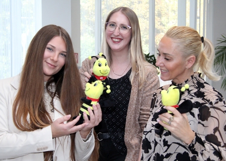 Giulia Dinius (v.l.n.r.), Julia Trienes und Anke Marabi zeigen die Kuschelbienen, die es als Dankeschön für die Kinder in der Weltsparwoche gibt. Die Sparkasse verschenkt zudem Memory-Games, Playmobil-Figuren und Ladekabel.