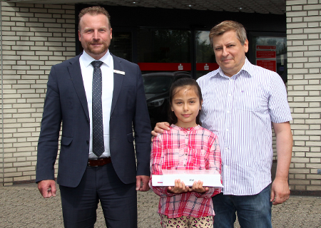 Die zehnjährige Sarrah-Leonie Herschowski gewann bei einem Gewinnspiel der Sparkasse am Niederrhein ein Tablet. Zur Preisübergabe in der Geschäftsstelle Schwafheim hatte sie ihren Vater Bernhard (rechts) mitgebracht. Roman Schönwald (links) gratulierte herzlich.