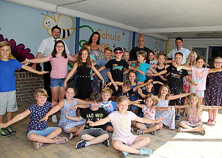 Kinder der Schule am Bienenhaus in Millingen summten und brummten bei der Vorstellung der neuen Bienenwand, die Sprayer Kai Hinz (Mitte, hinten) kurz zuvor fertiggestellt hatte. Schulleiterin Jasmin Brune und Severin Winnekens (ganz rechts) bedankten sich bei Julian de Vries von der Sparkasse für die Spende.    