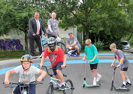 Sparkassenvorstand Frank-Rainer Laake (v.l.n.r.) sowie Michael Schmitz und Mathias Klaft-Turnau vom Verein StreetGrown schauen den Kids beim Biken und Scootern zu. Die Pumptrack-Anlage neben der Tennishalle ist am Samstag, 13. August, Schauplatz des ersten Laufs um den NRW-Pumptrack-Cup.