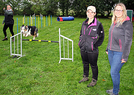 Saskia Pohl (vorne, links) und Kathrin Hüsch von der Sparkasse auf der Platzanlage des Vereins für Deutsche Schäferhunde in Veen. Hier springt gerade Australian Shepherd-Hündin Loki fehlerfrei über eines der Hindernisse. Ganz links: Lokis Frauchen Lena Altmann.