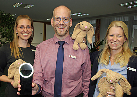 Michelle Laubinger (links), Gerd Heursen und Stefanie Aldenhoff mit dem Kuschelhasen Milo und dem Selfie-Licht fürs Handy. Diese und weitere Geschenke warten in der Weltsparwoche in allen 23. Geschäftsstellen der Sparkasse am Niederrhein auf kleine Sparer.