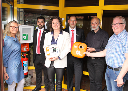 Heike Reiffen (v.l.n.r.), Nils Schwenner, Beate Richter, Norbert Kubik, Heiner Augustin und Wolfgang Brucksch mit dem neuen Defibrillator, der im Eingang vom Budberger Gemeindehaus zu finden ist.