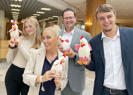 Emilia Koch, Anke Marabi, Trevor Fishwick und Dominik Peters zeigen die Kuschelhühner, die es als Dankeschön für die Kinder in der Weltsparwoche gibt. Die Sparkasse verschenkt zudem Kombinationsspiele, Trinkflaschen und Ladekabel.