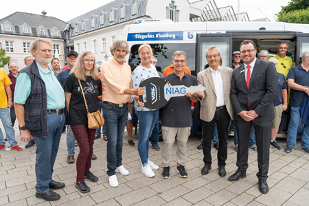 Übergabe des zweiten Bürgerbusses in Rheinberg. Vorne v.l.n.r.: Gerd Gersch, Susanne Grimm und Peter Bender vom Vorstand des Bürgerbus-Vereins Rheinberg, Astrid Kutscha (NIAG), Bürgermeister Dietmar Heyde, stellvertretender Landrat Günter Helbig und Benjamin Waldmann von der Sparkasse am Niederrhein.