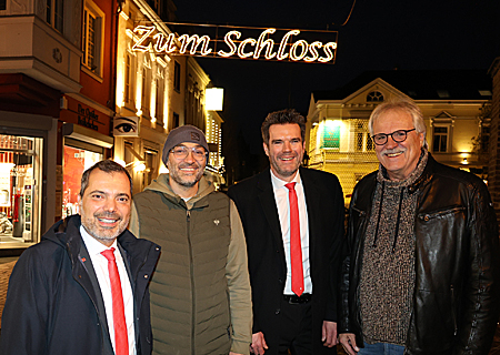 Freuen sich über den neuen, hell erleuchteten Schriftzug auf der Klosterstraße, der den Weg vom Altmarkt zum Schloss weist (v.l.n.r.): Giovanni Malaponti (Sparkasse), Stipe Madzar (Grafschafter Wirtshaus), Stefan Ertelt (Sparkasse) und Achim Reps von der ISG.