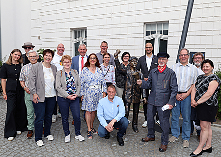 Einweihung der Bronzestatue, die vor dem Rathaus an Heinrich Graeven, den letzten Ausrufer von Alpen, erinnert. Carlo Hofmann (4. v. r.) lud dazu mit Handglocke und lauter Stimme ein, Bürgermeister Ludger Staymann (links daneben) erinnerte an den Ursprung der Kommunikation. Bernd Zibell (7. v. l.), Vorstand der Sparkasse am Niederrhein, bedankte sich bei den vielen Spenderinnen und Spendern, die das Projekt ermöglicht haben.