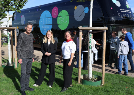 Martin Reichert, Leiter der Europaschule, und Lena Kempken sowie Alexandra de Lattré von der Sparkasse am Niederrhein vor dem FLiP2Go-Doppeldeckerbus, der allen 14- und 15-jährigen Schülern grundlegendes Finanz- und Wirtschaftswissen vermittelte.