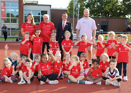 Die vier- bis siebenjährigen Running-Kids der LG Alpen präsentieren ihre neuen Laufshirts. Dahinter stehen Trainerin Carolin Stienen, Sportwart Wilhelm Schmitz, Tim Rütters von der Sparkasse und Trainer Malte Enbergs.
