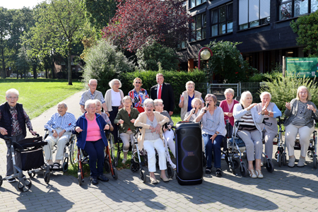 Die Bewohner des Evangelischen Altenzentrums mit neuer Soundbox im Xantener Kurpark. Ruth Pattay vom Förderverein und die Leiterin des Sozialen Dienstes, Beate Anhuf-Mölders, hatten Ludger Wehren von der Sparkasse am Niederrhein zum Platzkonzert eingeladen.