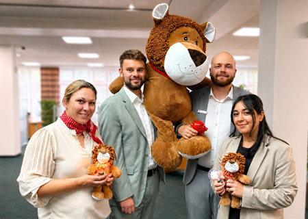 Nadine Lenzkes, Jan Gerlich, Benedikt Buck und Sudem Nur zeigen die Kuschel-Löwen und die LED-Glühbirnen, die es als Dankeschön für die Kinder in der Weltsparwoche gibt. Die Sparkasse verschenkt zudem noch Spiele und Ladekabel.